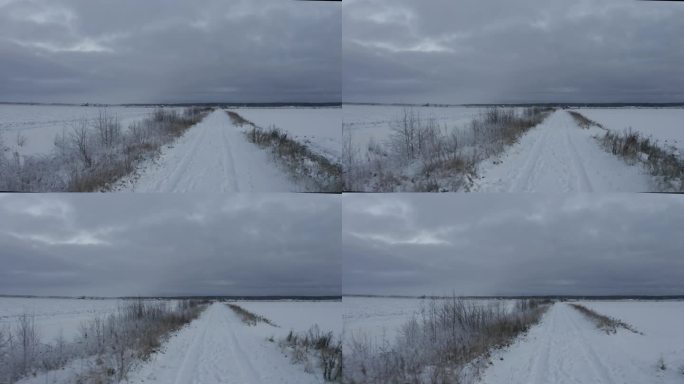 无人机拍摄的乡村道路上积雪上的汽车轨迹，背景是阴暗的黄昏天空