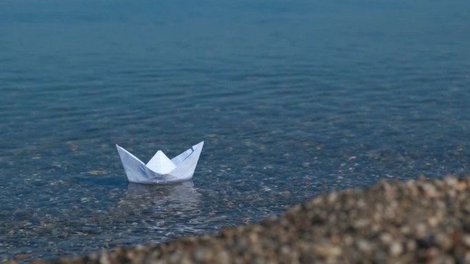 折纸船航行在蓝绿色的水。