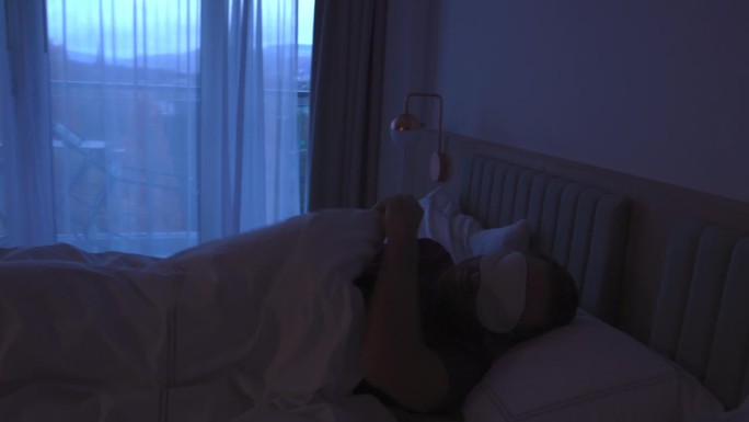 戴着眼罩在床上睡不着的男人