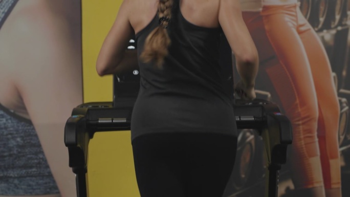 长头发的年轻女子在跑步机上。她背上的汗珠。有效减肥。