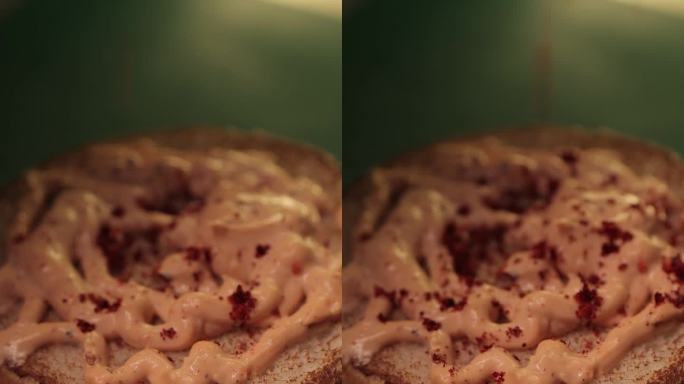 将香料粉末撒在烤汉堡面包上的汉堡酱上的特写垂直镜头