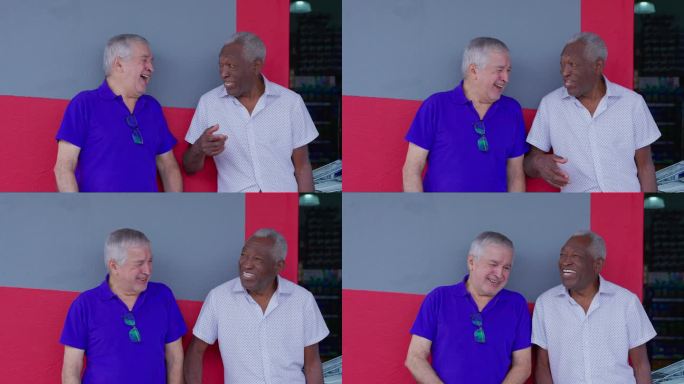 快乐的两个不同的男师兄靠在人行道上笑着。一个白人和非裔美国老年男性的互动