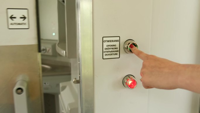 火车上一扇金属门的特写，上面有红绿相间的灯。女孩的手按下按钮打开了它。