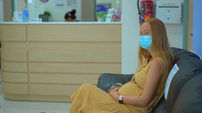 一位年轻的孕妇坐在候诊室里，耐心地等待轮到她去看医生。
