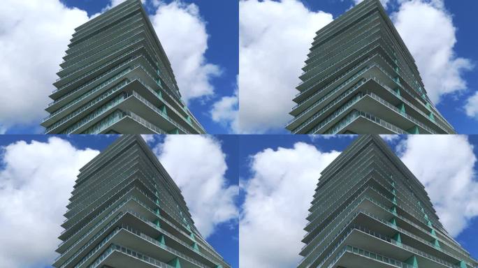 现代摩天大楼的低角度视图，有许多楼层和独特的角度设计。蓝色多云的天空在玻璃建筑的背景。建筑和景观的概
