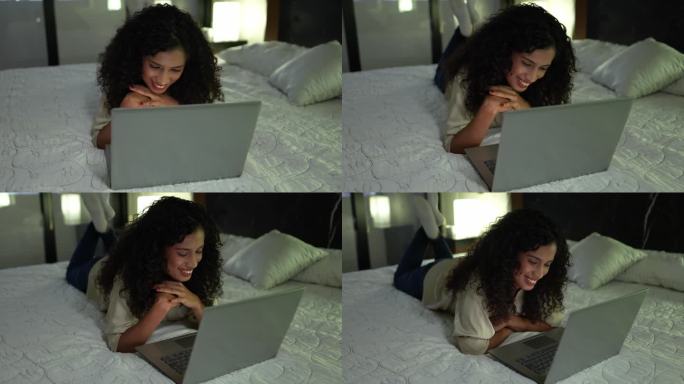 年轻女子用笔记本电脑躺在家里的床上看电影