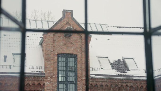 雪花飘过一扇窗户，勾勒出一座历史悠久的砖房。