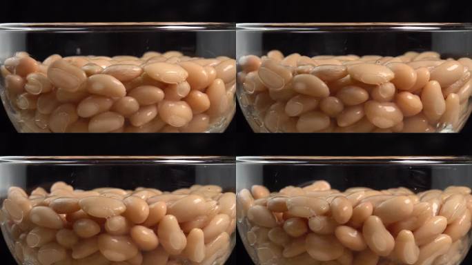 白芸豆罐头在玻璃碗里旋转。墨西哥菜的腌豆。有机蒸豆