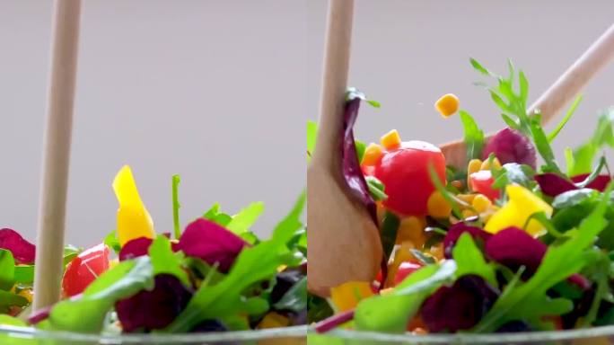 木勺在玻璃盘子里搅拌沙拉玉米西红柿黄瓜保加利亚黄辣椒芝麻菜叶子素食午餐减肥食谱特写女性的手