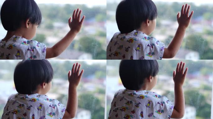 一个亚洲小孩望向窗外，希望到外面去玩。