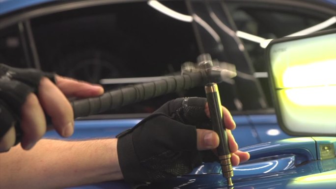 去除凹痕而不涂漆。PDR技术用于汽车车身修复。PDR。汽车修理店的机械师用工具修理车身上的凹痕。身体