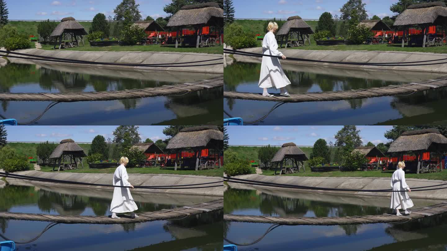 一个女孩走在池塘上的绳木桥上，保持着平衡。