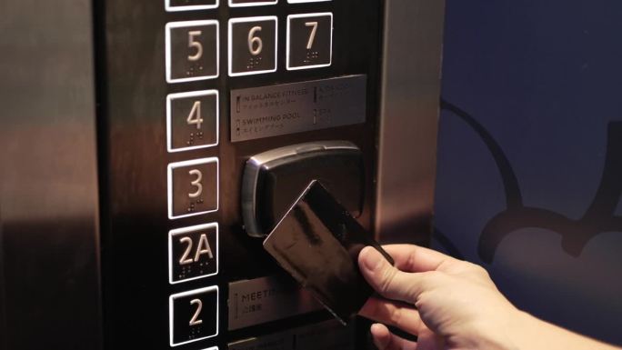 靠近女性的手，使用感应卡，非接触式数字钥匙解锁酒店电梯。数字或无密钥验证。