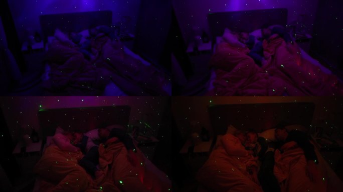 父母带着儿子睡在床上，床上有一盏白噪音RGB灯，灯上的星星投射在墙上