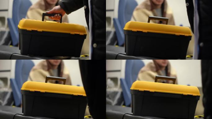 一个带有把手的黄黑相间的塑料箱子的特写被放置在救护车舱内，之后舱门关闭。