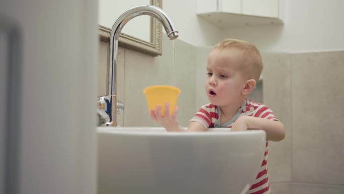 男婴孩子玩水溅流水龙头水槽在浴室握住模具