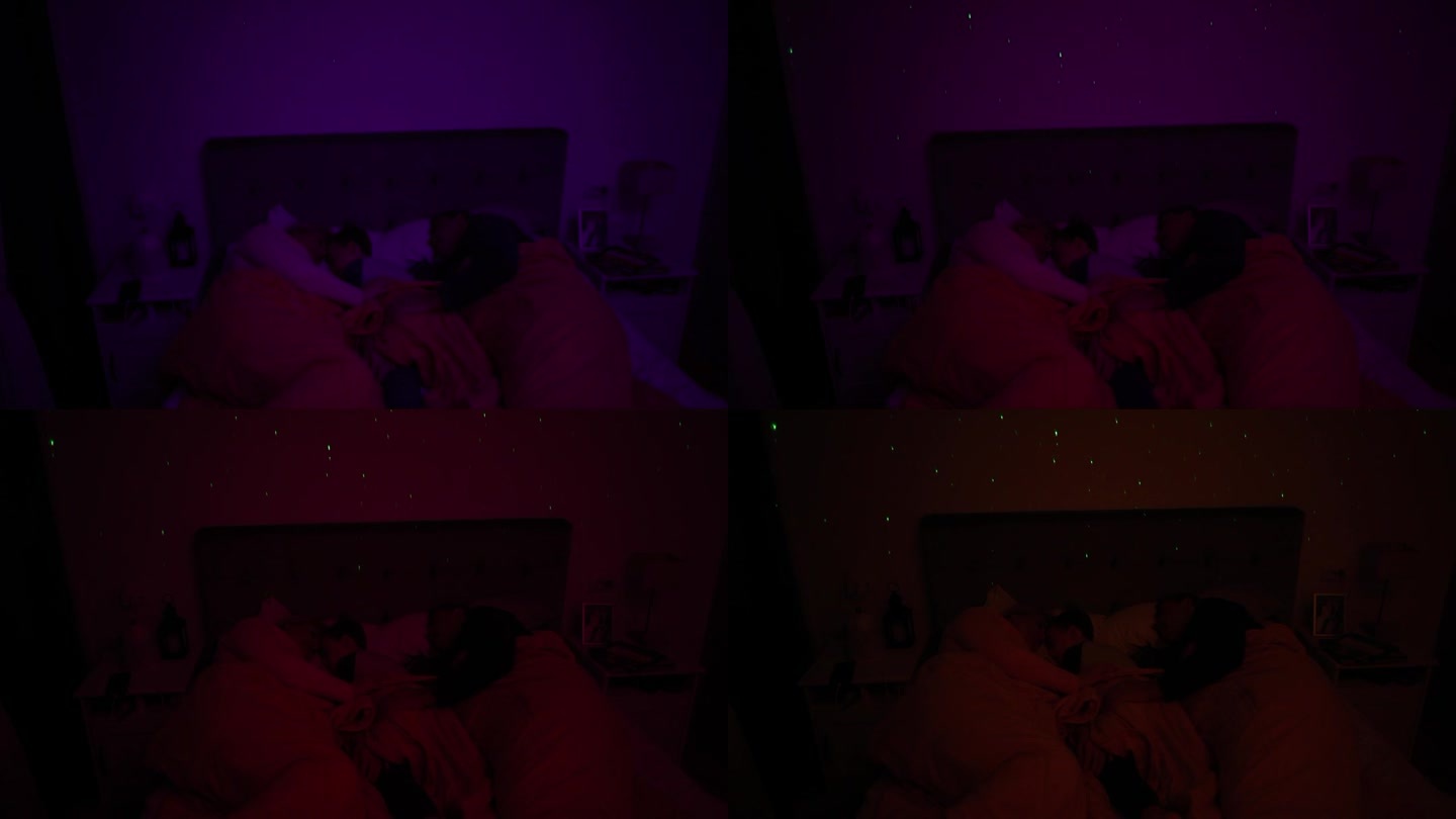 白人家庭，父母带着儿子睡在床上，床上有一盏白噪音RGB灯，灯上的星星在墙上投射