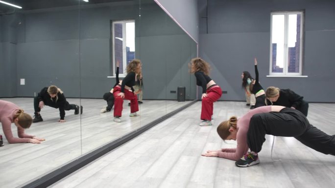女孩跳舞。跳舞前的热身课。六个年轻女孩站在镜子前做腿部肌肉伸展运动。