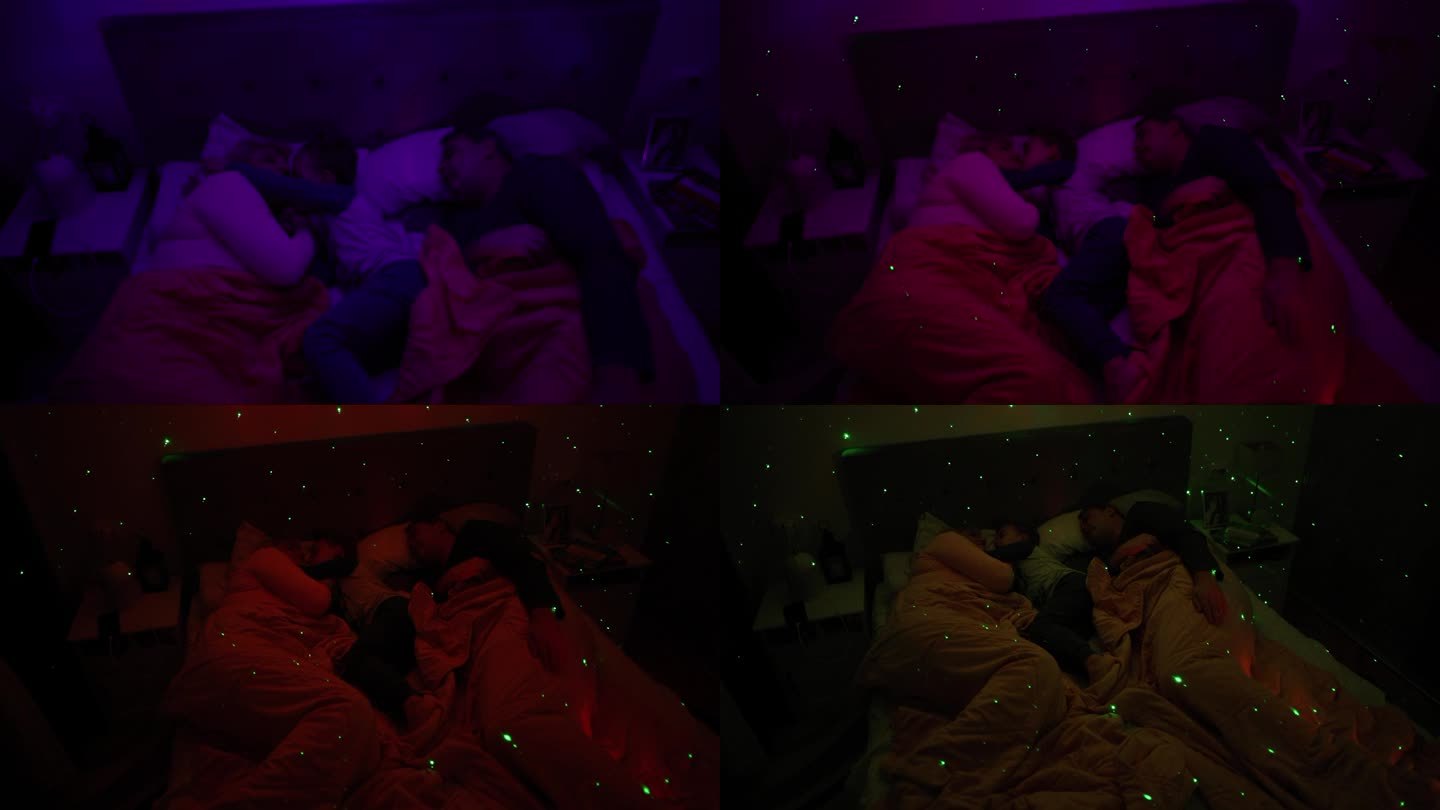 白人父母带着儿子睡在床上，床上有一盏白噪音RGB灯，灯上的星星在墙上投射
