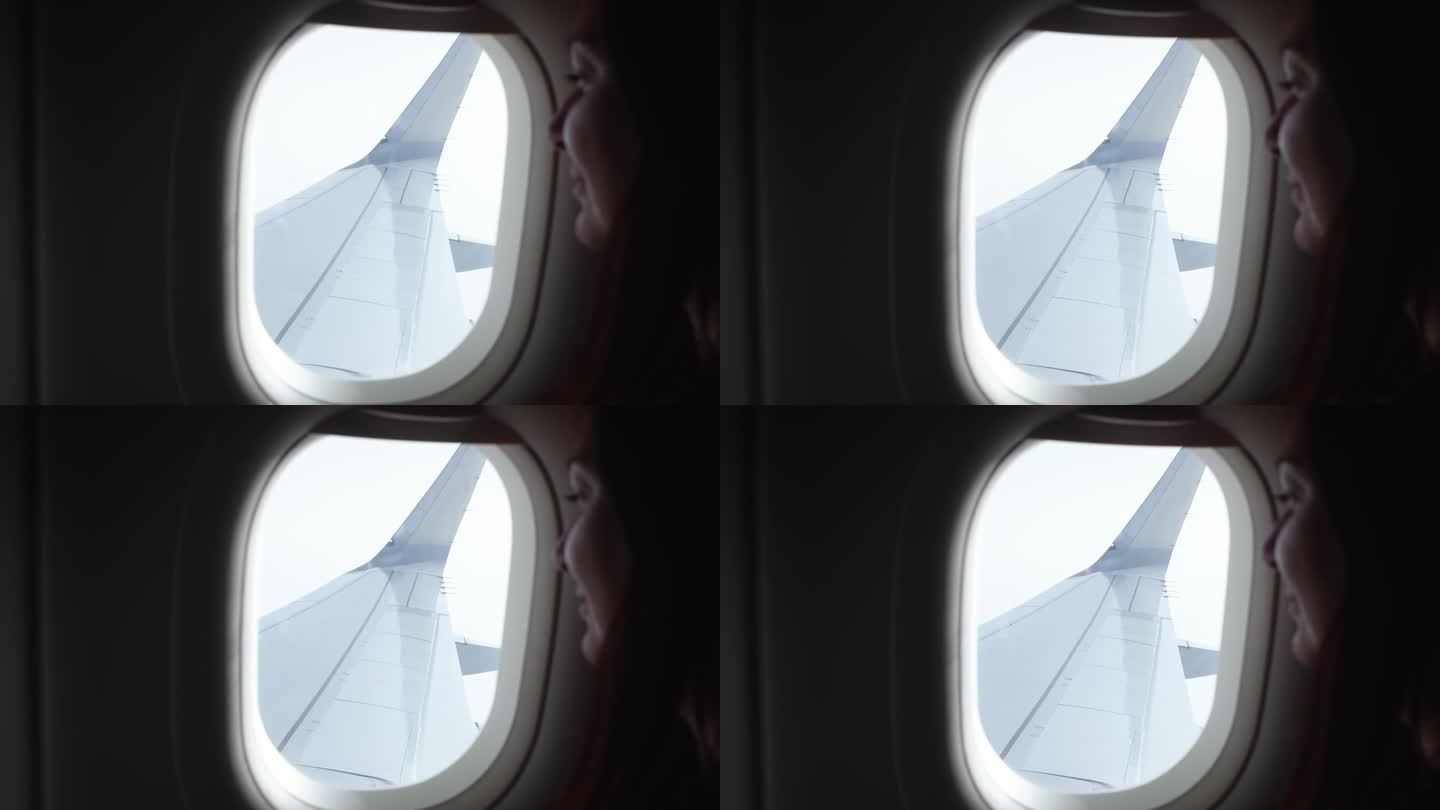 手持拍摄的微笑的女人向窗外看飞机