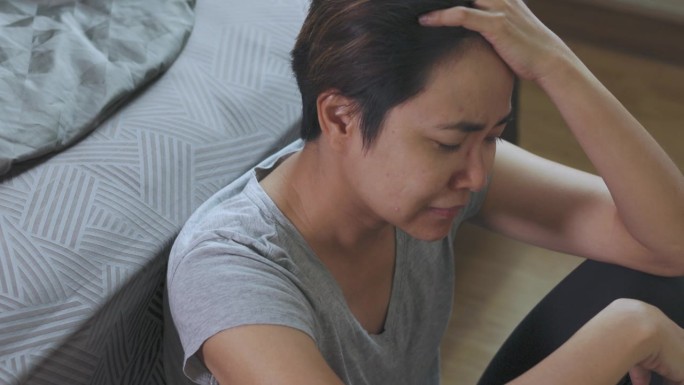 遭受虐待、暴力和离婚后果的亚洲女性的特写，她在卧室地板上嚎啕大哭，表达着心碎和绝望的痛苦。