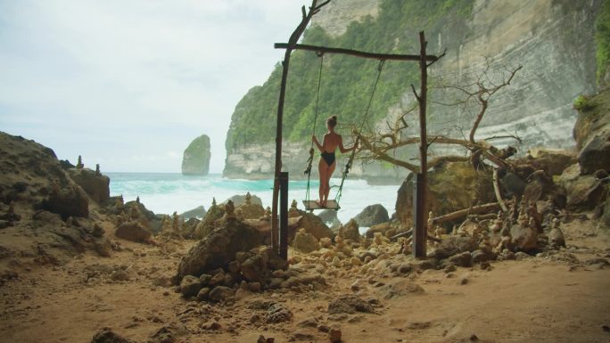 宁静的海景和孤独的秋千。宁静的海边，女人在沙滩上荡秋千，俯瞰蔚蓝的海浪。