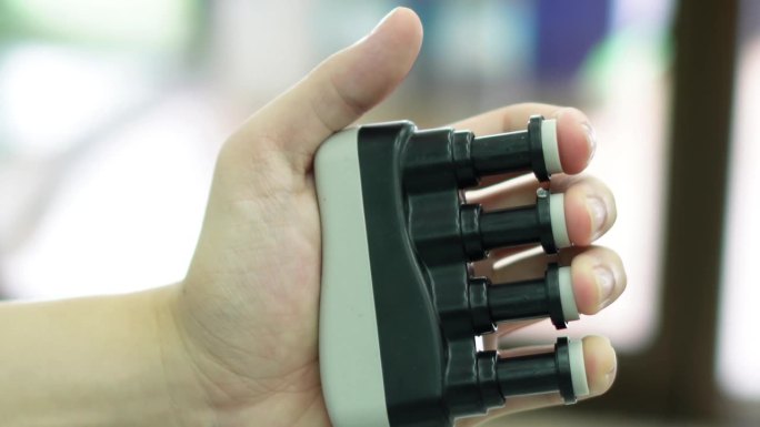 视频图像的物理治疗师使用小号式的手指锻炼装置在诊所。