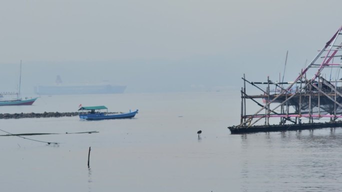 白天，一艘小船驶过停靠在南榜渔村港口周围的渔网和渔船