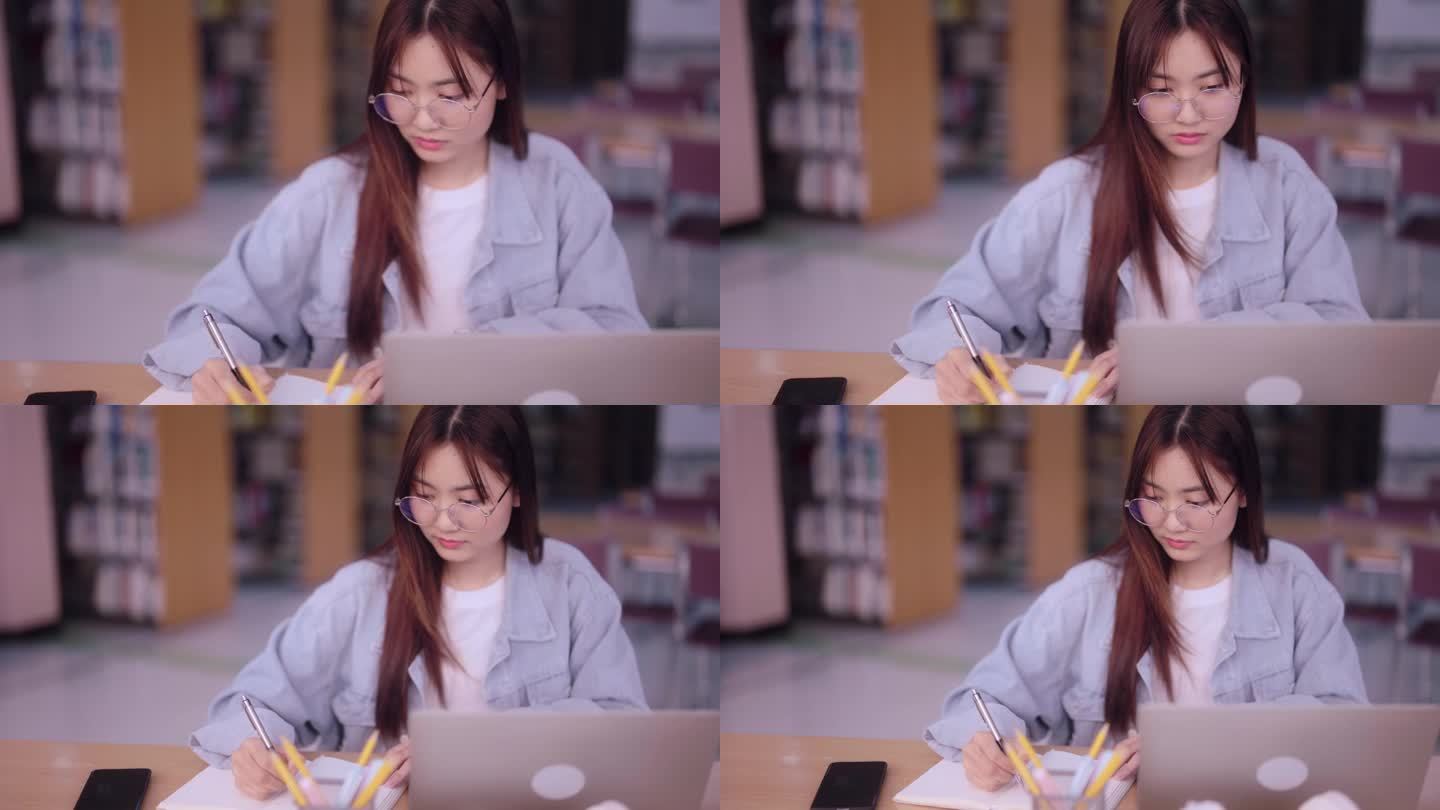 一名专注的亚洲女学生在大学图书馆用笔记本电脑记录从互联网上获取的信息。展示有效利用网上资源的学术目的