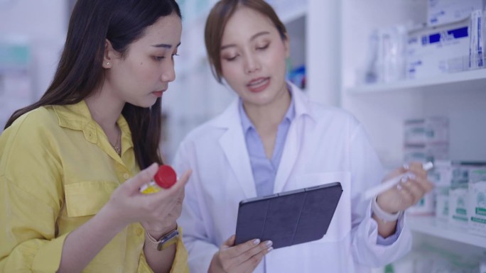 年轻的专业药剂师在药店帮助漂亮的女顾客推荐和咨询药物。