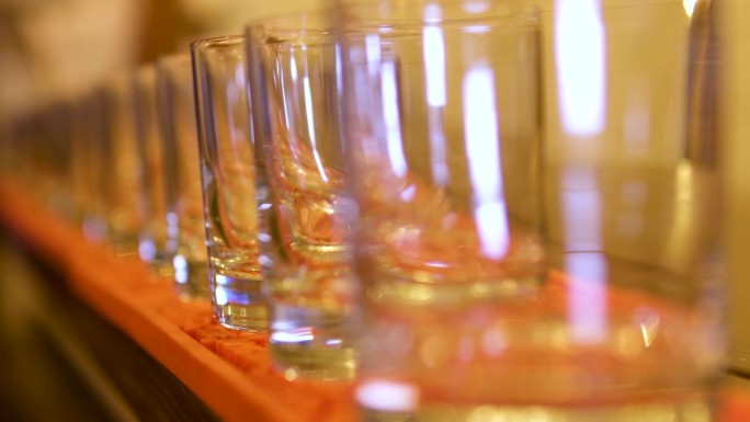 空玻璃玻璃杯站在一条线上改变焦点从第一到最后美丽的背景模糊橙色桌游戏与锐利庆祝餐厅酒吧柜台