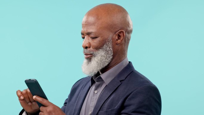 有智能手机的商界资深黑人，在蓝色背景下上网浏览有趣的表情包或社交网络。在工作室执行应用程序，社交媒体