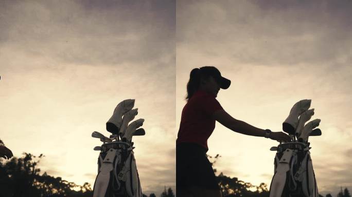 日落时分，一名中国女高尔夫球手在高尔夫球场拿起高尔夫球袋中的球杆