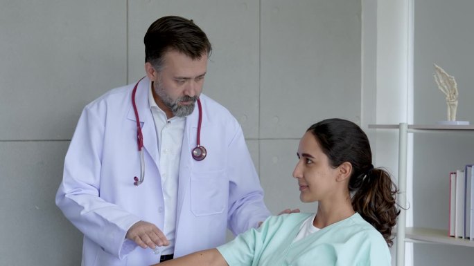 混血中年男医生举起女病人右手检查并观察进一步治疗过程。
