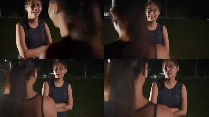 两个年轻的亚洲女性朋友在跑道上跑了一晚后站在那里聊天