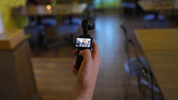 男性手在室内操作使用大疆Osmo口袋3万向节相机的特写镜头。