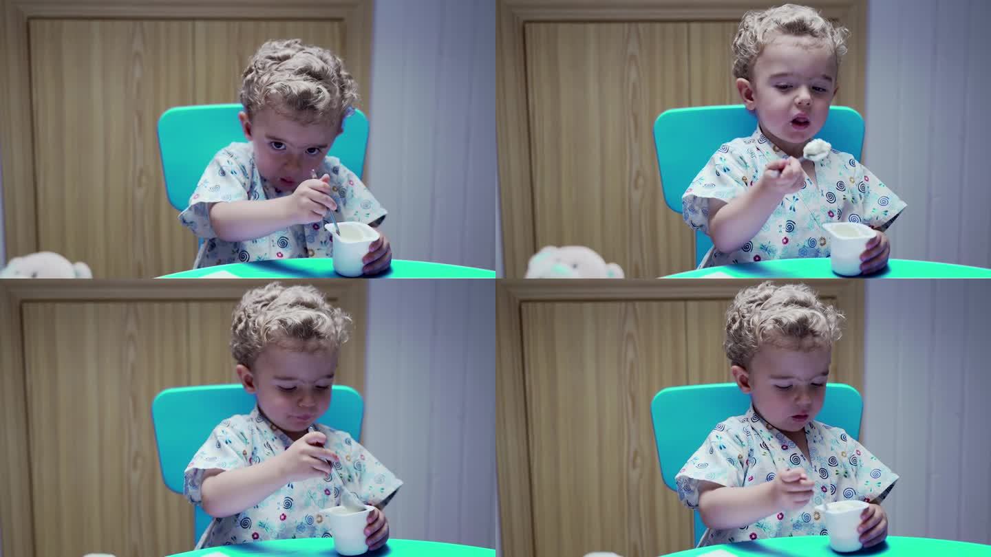 小男孩坐在桌子旁，用碗喝牛奶。