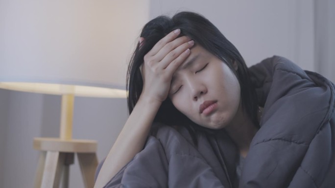 美丽的亚洲女人在家里躺在卧室的床上有抑郁和悲伤，保健和医疗的概念