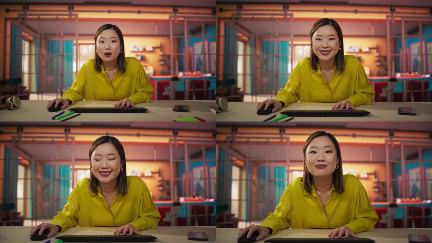 屏幕视角:美丽的亚洲女人坐在一张桌子上，在一个舒适的彩色公寓和使用电脑。微笑的女性成年人点头，在网上