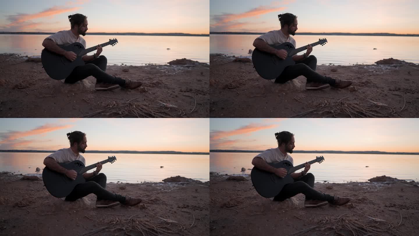 日落时分，在西班牙阿利坎特的托雷维耶哈粉红湖边，一个年轻人在沙滩上拿着吉他弹和弦的剪影