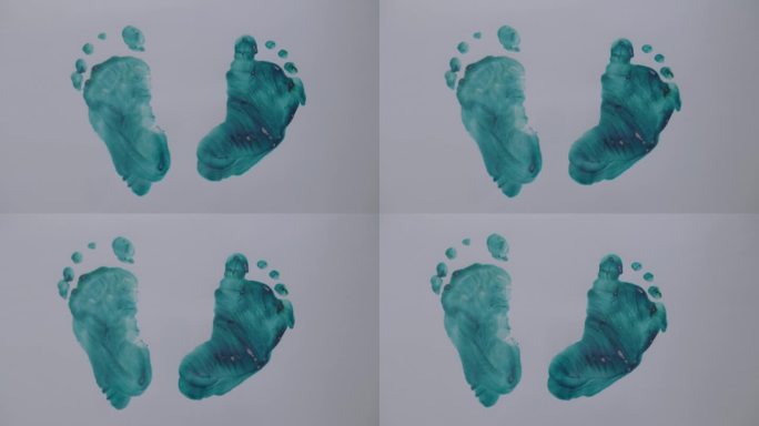 白色背景纸上婴儿脚的绿色印记特写