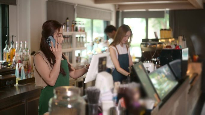 年轻的亚洲服务意识的咖啡师与顾客在咖啡店