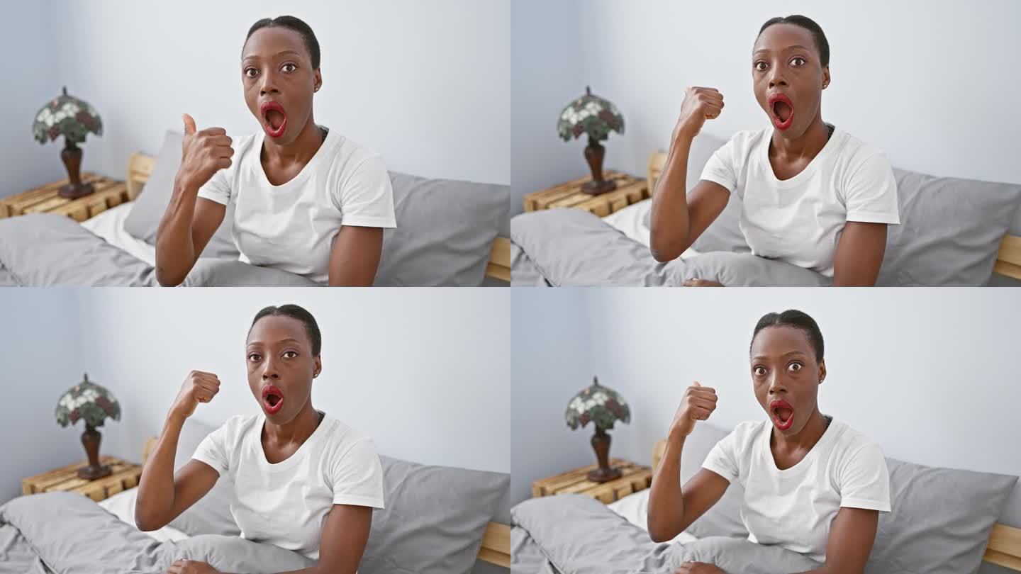 惊讶的非裔美国女人在卧室里，躺在床上带着惊讶的表情，眩晕地指着，嘴巴张得很大!