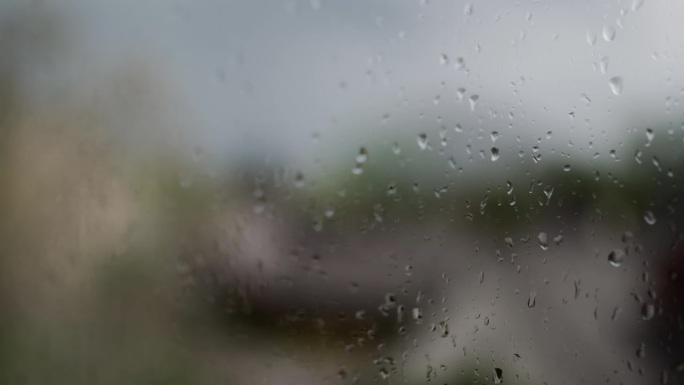 迷人的雨滴在下雨天优雅地从窗户倾泻而下，捕捉到宁静舒缓的氛围。