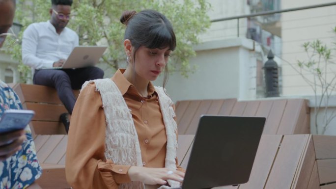 年轻的商务女士在户外共享办公空间使用笔记本电脑