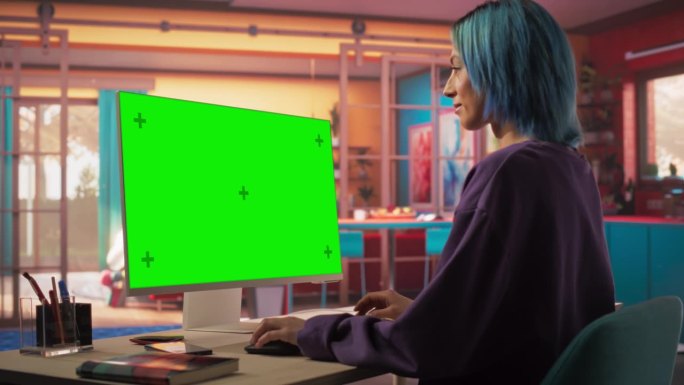弧线拍摄肖像美丽的时尚女人与蓝色头发使用现代桌面电脑与绿屏模拟显示。创意女性设计师和程序员从时尚之家