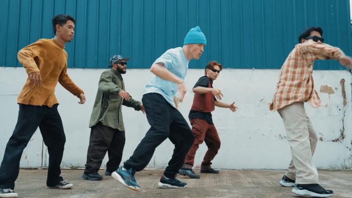 一群街舞编导在墙上一起跳街舞。嘻哈。