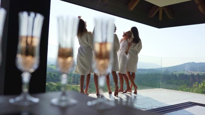 香槟笛子的特写，背景是穿着浴袍的女人。