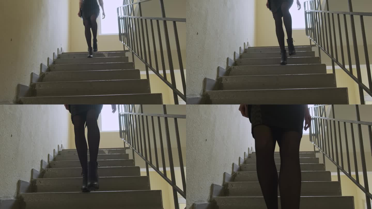 优雅的女孩穿着裙子走下住宅楼的混凝土楼梯。正面，光线从窗户照过来