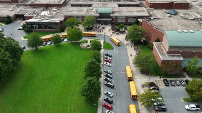 校车来接送学生时，学生们在公立学校的校园大楼里。美国教育中的多元化DEI主题。天线。